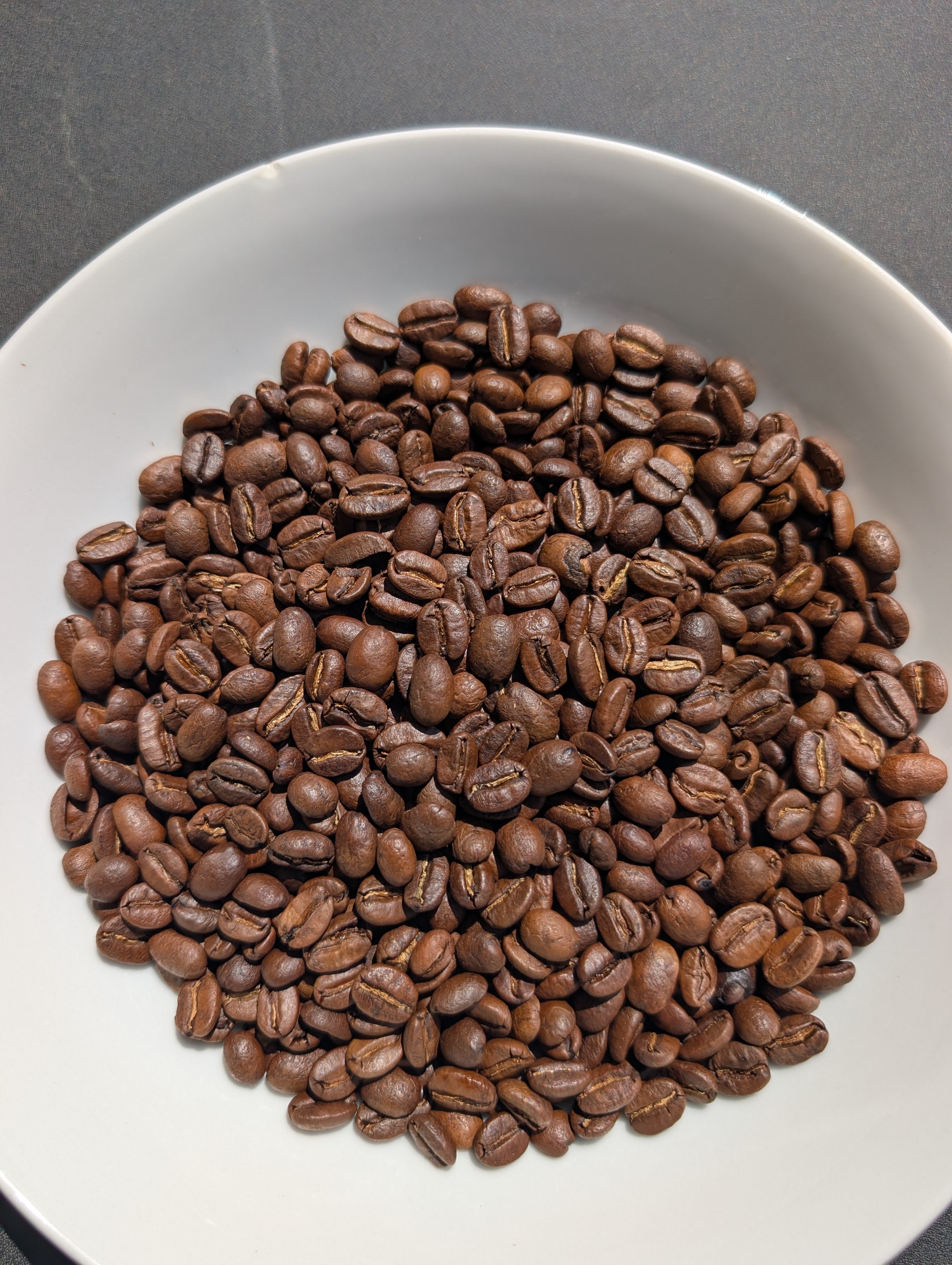 O.G. medium-dark whole coffee beans in a white bowl